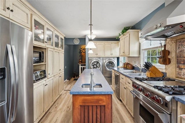 2106 Kasold Dr, Lawrence, KS 66047 - kitchen with independent washer and dryer, cream cabinets, a sink, wall chimney exhaust hood, and stainless steel appliances