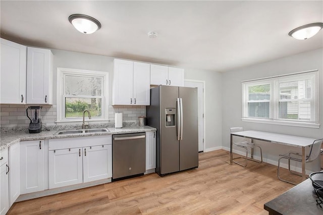 kitchen featuring a healthy amount of sunlight, appliances with stainless steel finishes, a sink, and decorative backsplash