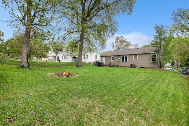 view of yard with fence, a fire pit, and central AC