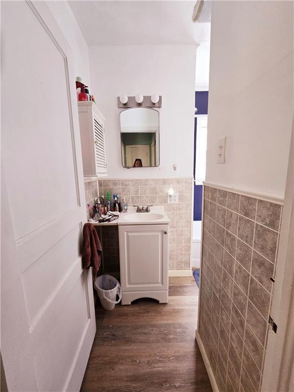 bathroom with tile walls, wainscoting, wood finished floors, and vanity