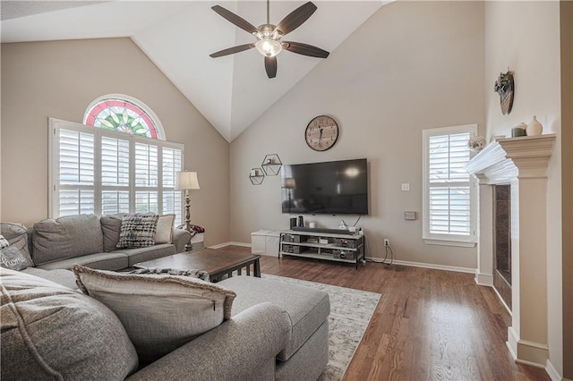 living room with a fireplace, a ceiling fan, high vaulted ceiling, plenty of natural light, and wood finished floors