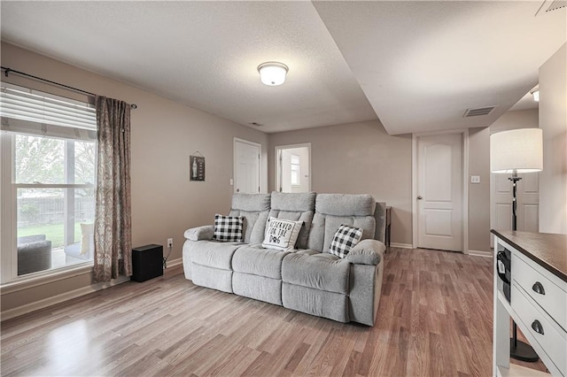 living area with light wood-style floors, baseboards, and plenty of natural light