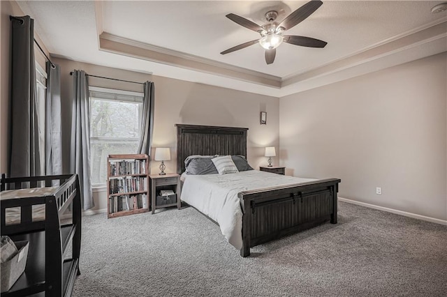 bedroom with a tray ceiling, ornamental molding, carpet flooring, and baseboards