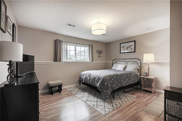 bedroom featuring wood finished floors, baseboards, and a textured ceiling