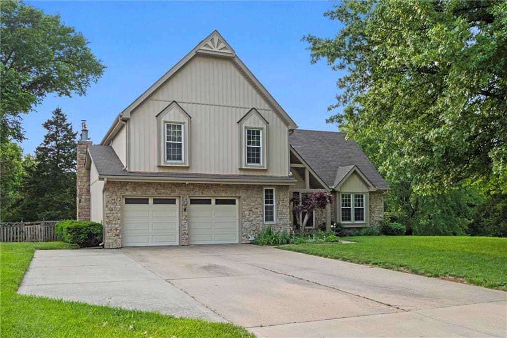 620 S Hickory Trl, Lansing, KS 66043 - view of front of property featuring stone siding, an attached garage, driveway, a chimney, and board and batten siding