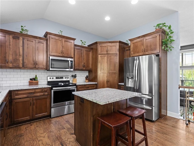 5084 NW Timberline Dr, Riverside, MO 64150 - kitchen featuring dark wood-style flooring, lofted ceiling, a kitchen island, tasteful backsplash, and stainless steel appliances