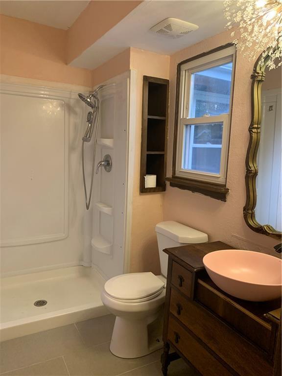 308 NW Shamrock Ave, Lees Summit, MO 64081 - bathroom featuring tile patterned floors, a shower stall, vanity, and toilet