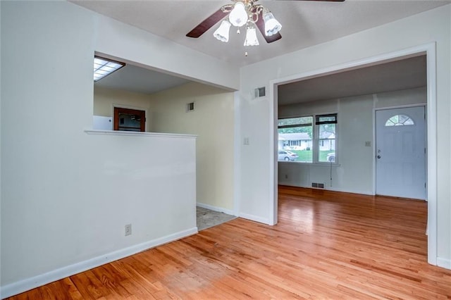 empty room featuring ceiling fan, light wood-style floors, and baseboards