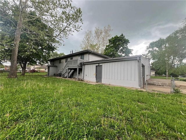 back of property featuring a wooden deck, a yard, stairway, and fence
