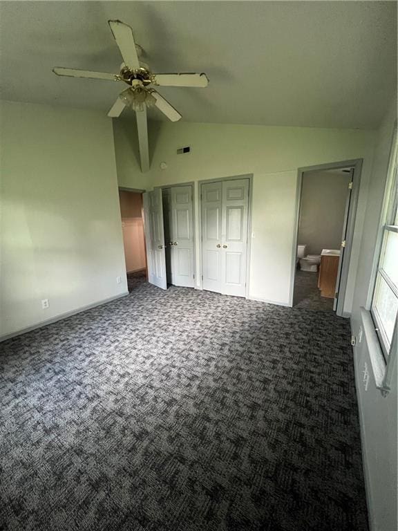 unfurnished bedroom featuring visible vents, multiple closets, vaulted ceiling, and carpet