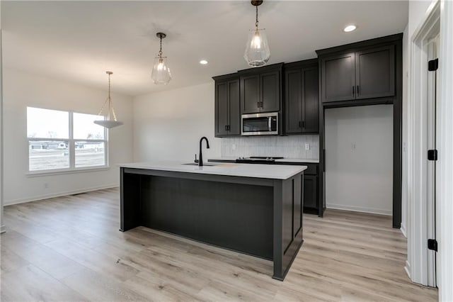 16502 S Stagecoach St, Olathe, KS 66062 - kitchen featuring stainless steel microwave, a sink, backsplash, light countertops, and light wood-style floors
