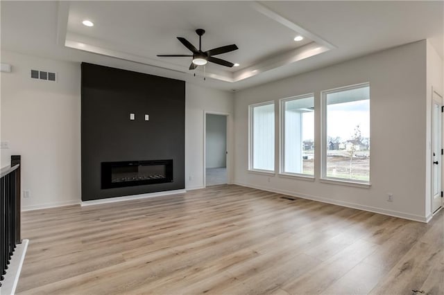 16502 S Stagecoach St, Olathe, KS 66062 - unfurnished living room with a raised ceiling, light wood finished floors, a ceiling fan, a large fireplace, and recessed lighting