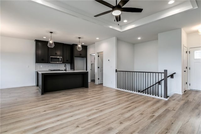 16502 S Stagecoach St, Olathe, KS 66062 - kitchen with stainless steel microwave, recessed lighting, a tray ceiling, light wood-style floors, and backsplash