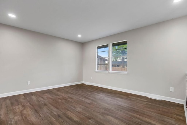 empty room featuring recessed lighting, baseboards, and dark wood-type flooring