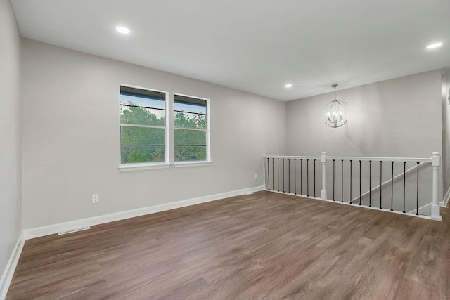 unfurnished room with recessed lighting, baseboards, wood finished floors, and a chandelier
