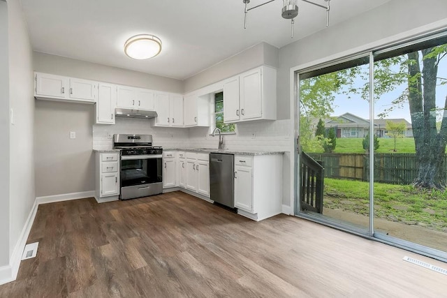 kitchen featuring appliances with stainless steel finishes, white cabinets, backsplash, and under cabinet range hood