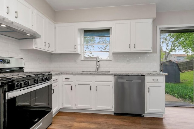 kitchen with under cabinet range hood, white cabinets, appliances with stainless steel finishes, and a sink