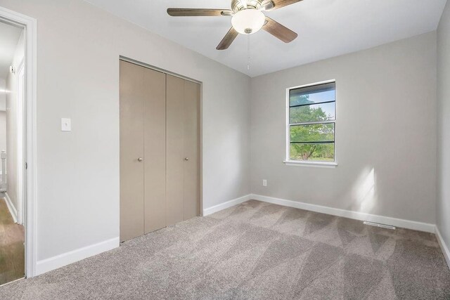 unfurnished bedroom featuring a closet, baseboards, ceiling fan, and carpet flooring