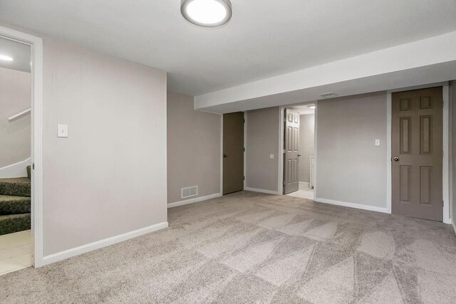 finished below grade area with carpet flooring, baseboards, visible vents, and stairway