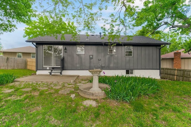 rear view of house with fence, a yard, and a patio area