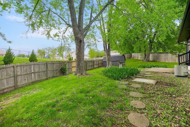 view of yard with an outbuilding, a fenced backyard, and a storage unit
