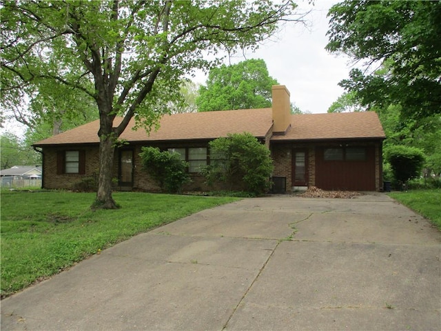 single story home with brick siding, a front lawn, a chimney, and concrete driveway