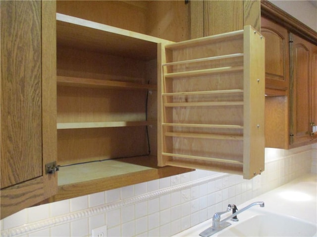 interior details featuring light countertops, a sink, brown cabinets, and tasteful backsplash