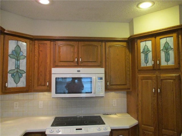 kitchen featuring light countertops, glass insert cabinets, and white appliances