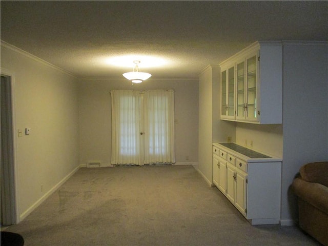 unfurnished dining area featuring baseboards, ornamental molding, a textured ceiling, and light colored carpet