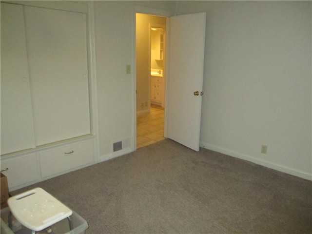 unfurnished bedroom with baseboards, carpet, and visible vents