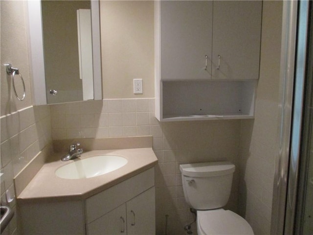 bathroom with vanity, toilet, and tile walls