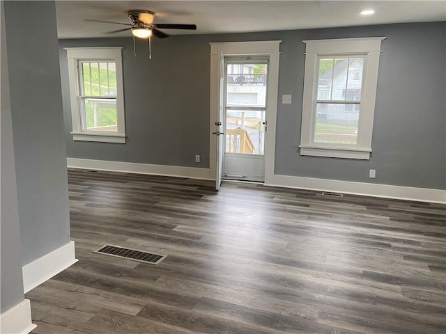 empty room with visible vents, baseboards, wood finished floors, and a wealth of natural light
