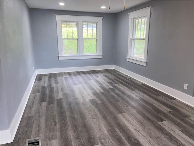 spare room with baseboards, dark wood-style flooring, and visible vents