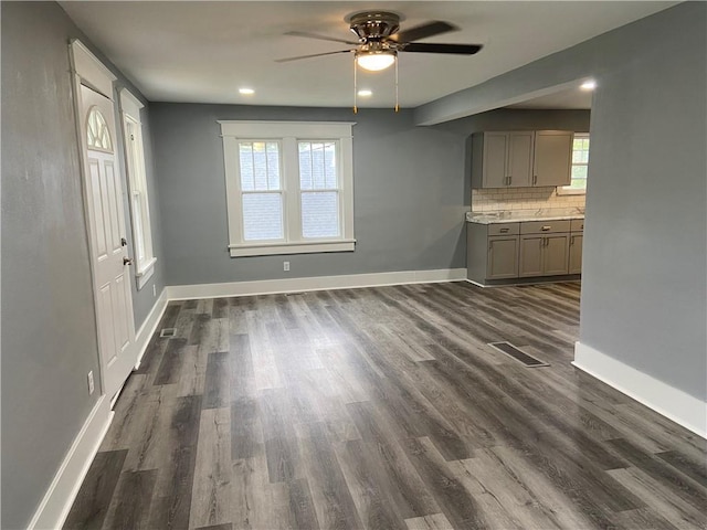 unfurnished dining area with baseboards, a ceiling fan, dark wood-style floors, and visible vents