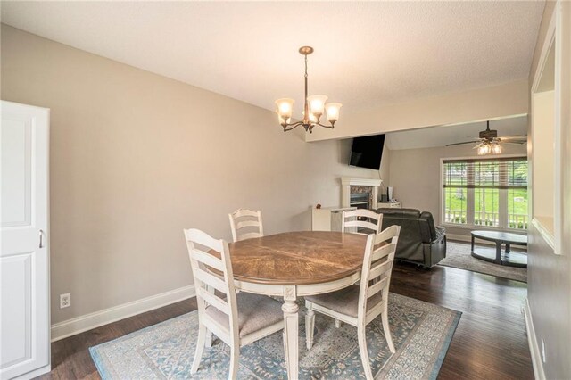15 Baber Cir, Camden Point, MO 64018 - dining area featuring dark wood-type flooring, a fireplace, baseboards, a chandelier, and ceiling fan