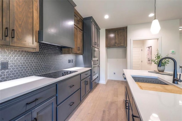 16567 S Stagecoach St, Olathe, KS 66062 - kitchen featuring black electric cooktop, a sink, premium range hood, light wood-type flooring, and light countertops