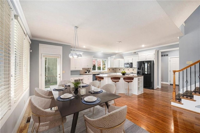 14475 Chadwick St, Leawood, KS 66224 - dining space with baseboards, crown molding, wood finished floors, and stairway