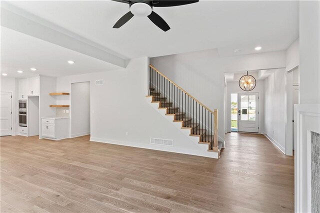 7015 Forest Lks, Parkville, MO 64152 - unfurnished living room featuring stairway, light wood-type flooring, a chandelier, a ceiling fan, and recessed lighting