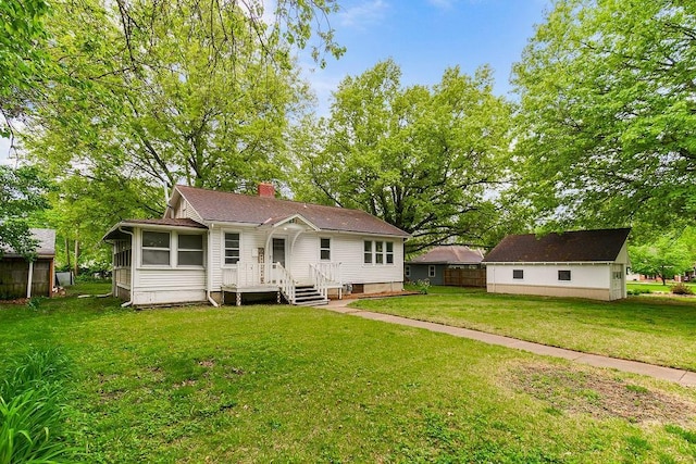 rear view of property with a sunroom, a yard, and a chimney