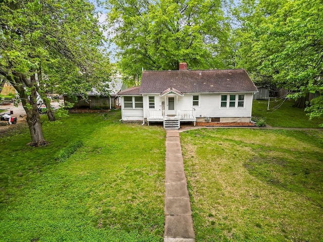 back of property featuring a lawn, a deck, a chimney, and a shingled roof