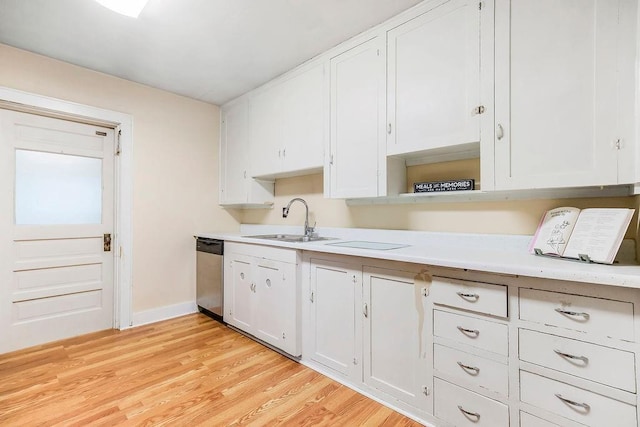 kitchen with stainless steel dishwasher, white cabinets, a sink, and light countertops