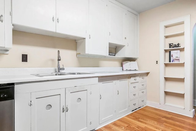 kitchen with stainless steel dishwasher, light wood-type flooring, light countertops, white cabinetry, and a sink