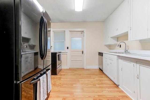 kitchen with light wood-type flooring, light countertops, white cabinetry, a sink, and stainless steel appliances
