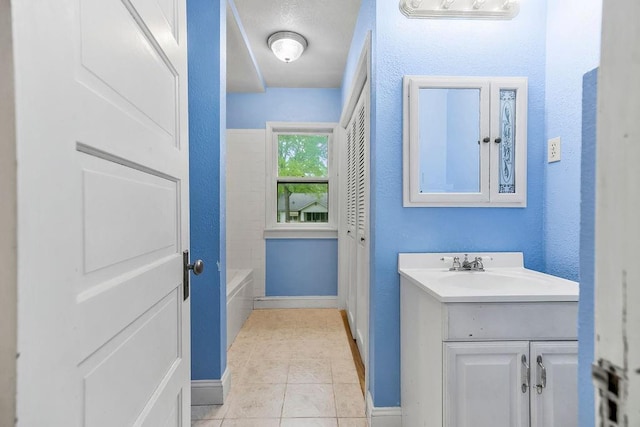 bathroom with baseboards, tile patterned flooring, and vanity