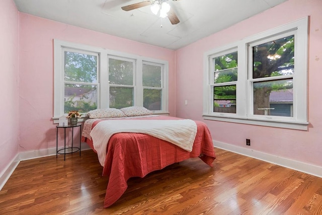 bedroom with baseboards, multiple windows, and wood finished floors