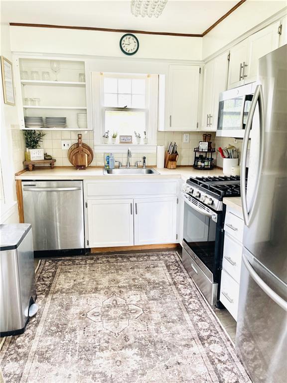 336 E Park St, Olathe, KS 66061 - kitchen featuring stainless steel appliances, a sink, decorative backsplash, light countertops, and white cabinets