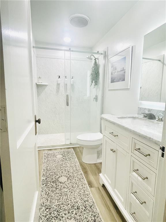 336 E Park St, Olathe, KS 66061 - full bath with a stall shower, wood finished floors, toilet, and vanity