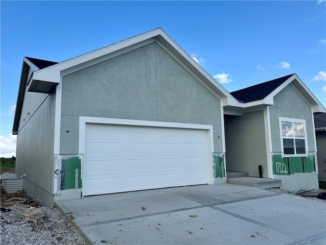 ranch-style house featuring a garage, stucco siding, and driveway