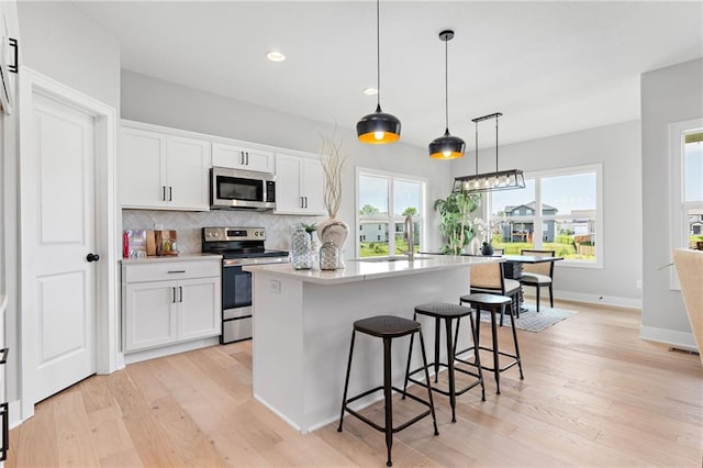 kitchen with a sink, decorative backsplash, white cabinets, and stainless steel appliances