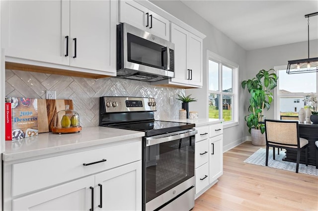 kitchen with white cabinets, stainless steel appliances, light wood-style floors, and tasteful backsplash